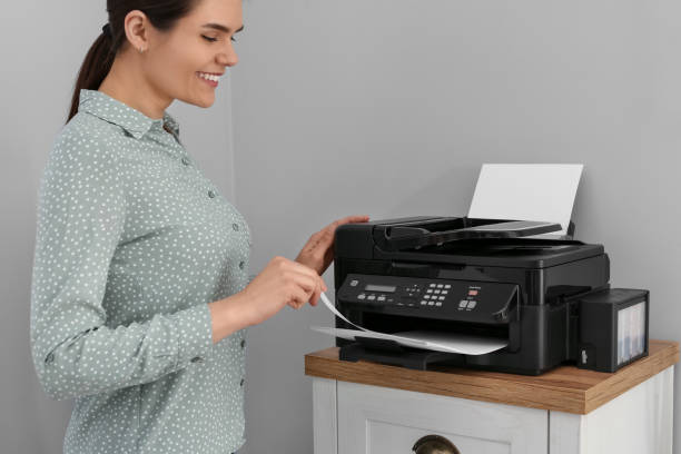 istock Woman using modern printer on chest of drawers at home 1709000556