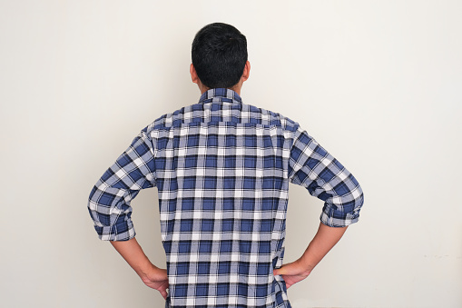 Back view of a man read something with both hands on his waist