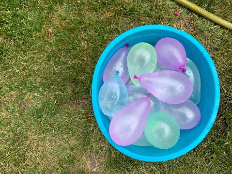 Bucket full of water balloons on the grass from above