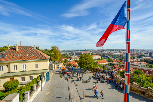 A view from Prague Castle showing downtown Prague, Czechia, or Czech Republic, and the river Vltava in the distance with the Czech flag flying in the foreground.