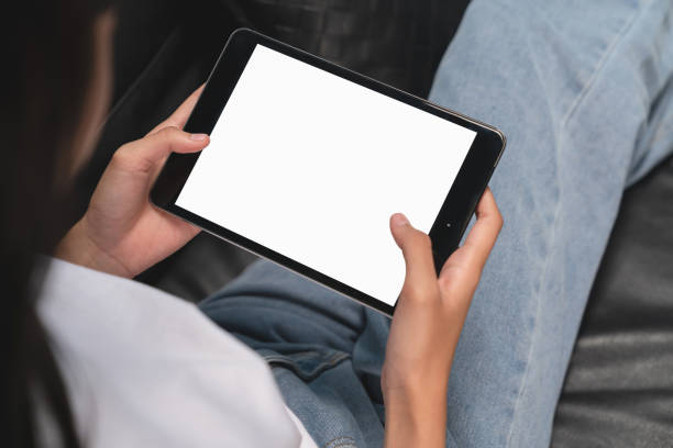 istock Woman hand holding digital tablet with blank screen for graphic display montage, on the sofa in the living room. 1709184652
