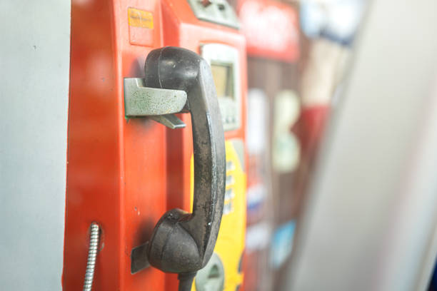 The antique analog payphone or telephone box, close-up and selective focus at handset. Vintage technology and equipment object photo.