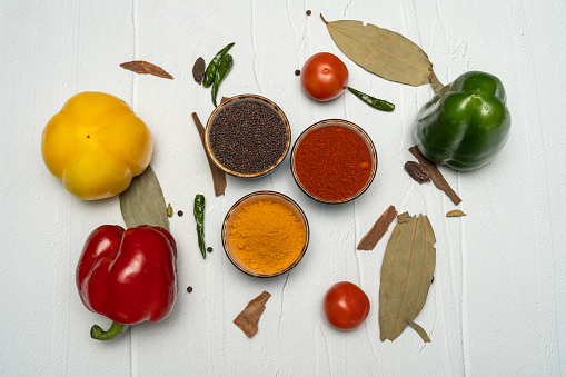 Bowl with aromatic paprika powder and fresh bell peppers isolated on white