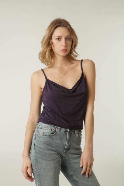 Female model wearing purple camisole cotton top and denim pants. Classic and simple summer fashion. Studio shot. Female model wearing purple camisole cotton top and denim pants. Classic and simple summer fashion. Studio shot. viscose stock pictures, royalty-free photos & images