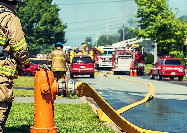 A firefighter stands at ready to turn on a backup fire hydrant on the scene of a house fire.