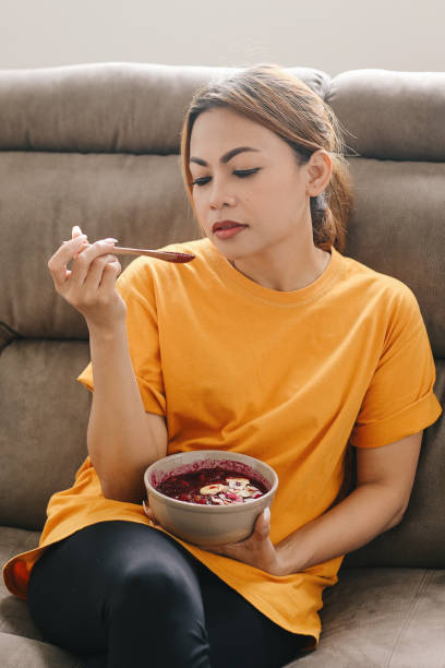istock Hispanic Woman Eating Smoothie at Sofa 1709352400