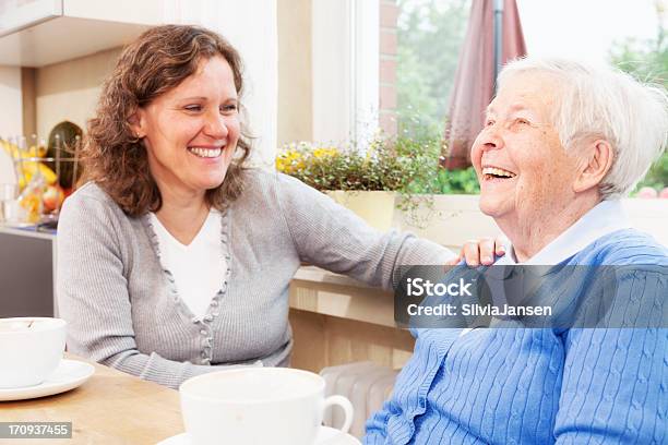 Junge Und Ältere Frau Trinken Kaffee Und Lachen Stockfoto und mehr Bilder von Alter Erwachsener - Alter Erwachsener, Sozialarbeit, Seniorinnen