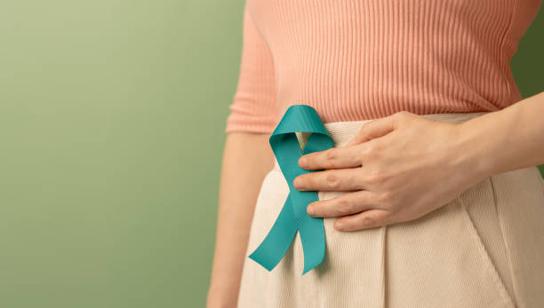 Ovarian and Cervical Cancer Awareness. Woman Holding Teal Ribbon on Lower Abdomen, Uterus, Female Reproductive System, Women's Health, PCOS and Gynecology stock photo