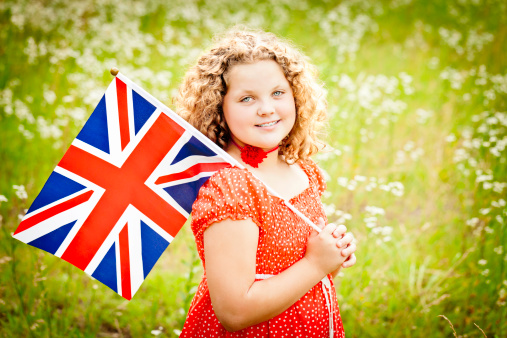 Beautiful 11 year old girl with a British flag standing in a field of wildflowers