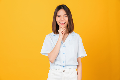 Happy smiling young woman hand pointing to the side, isolated on yellow background.