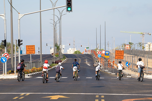 Rishon Lezion, Israel - September 25, 2023: Teenage boys ride on bicycles along a highway empty of cars during the holiday of Yom Kippur