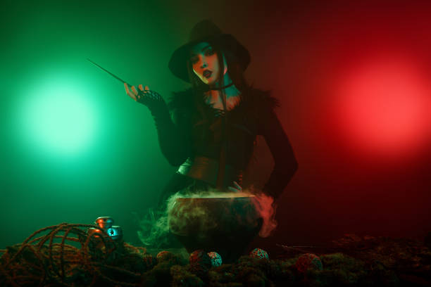 Woman with a magic wand in a hat and coat on black background