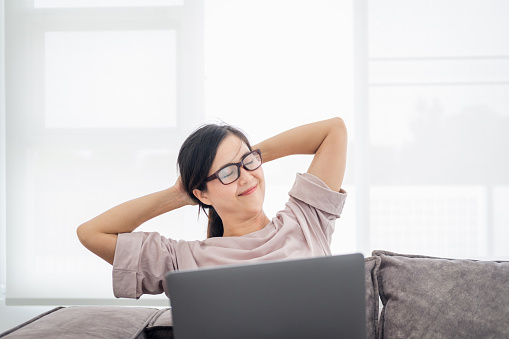 Office syndrome concept. mature middle age asian woman feeling pain in neck and shoulder after working on computer laptop for a long time. She stretches to relax her muscles