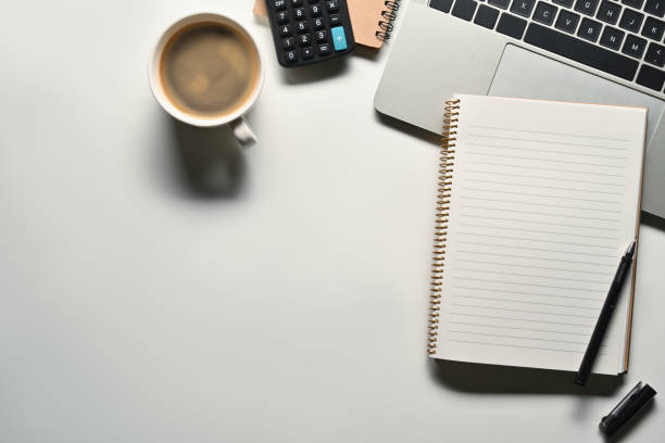 istock Blank notepad, laptop, calculator and coffee cup on white office desk. Top view with space for your text 1709467573