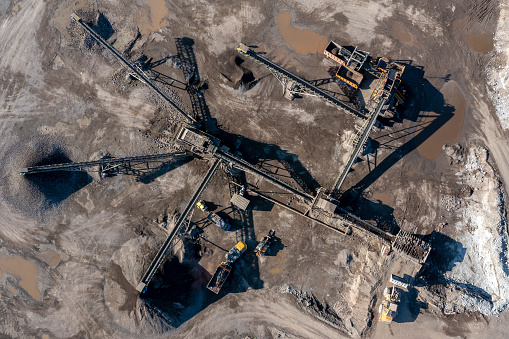 Conveyor belts, heaps of gravel and bulldozer in a gravel pit from directly above.