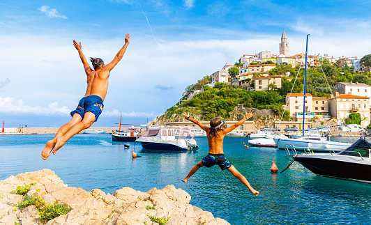Happy family jumping off the rock into the sea (Croatia,Europa)