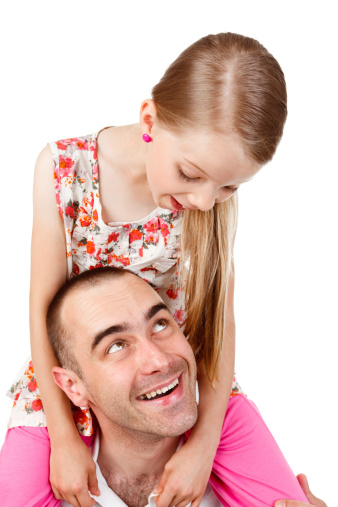 Portrait of a father with daughter sitting on his shoulders. They are looking at each other and laughing.