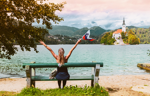 Travel destination in Slovenia- tour tourism on Bled lake, Woman tourist holding Sloven flag