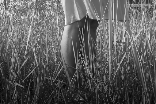 a woman's feet standing on a field of weeds.