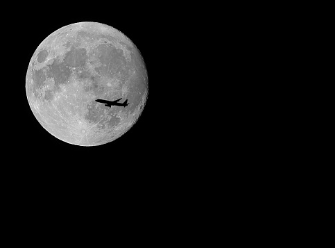 amazing giant super moon and silhouette of the plane flying high in the black sky