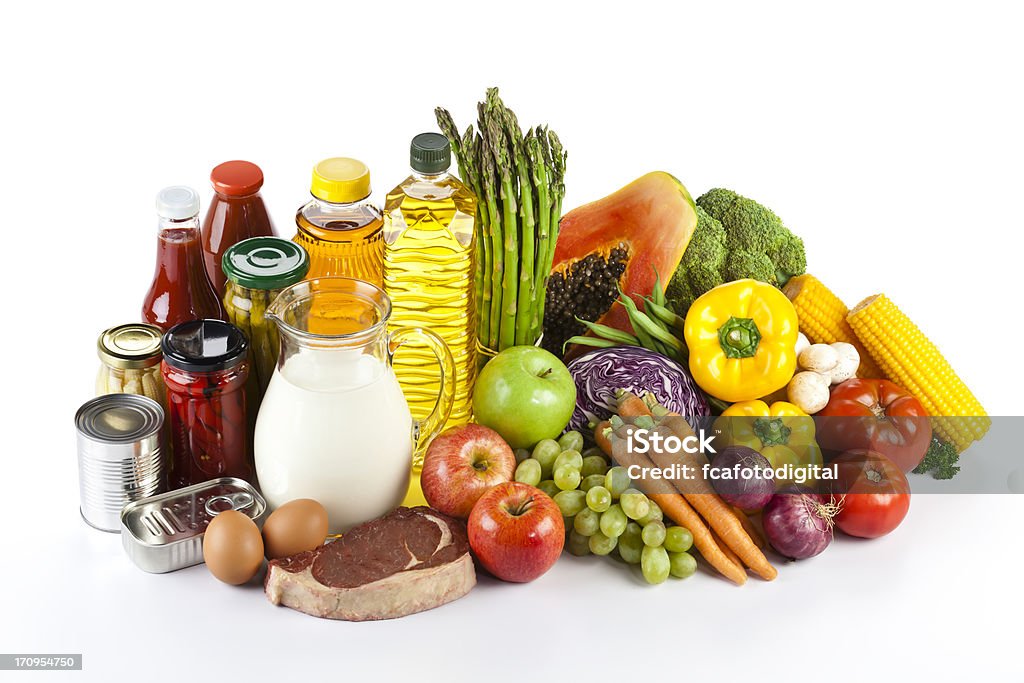 Large group of groceries arranged neatly on white table Large Group of Groceries Isolated on White Background. Includes Canned Food, Milk, Meat, Fruits and Vegetables. Supermarket Stock Photo