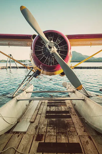 A seaplane sits on a dock in early morning light.