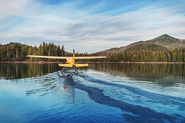 A float plane departs from a still inlet in Southern Alaska.