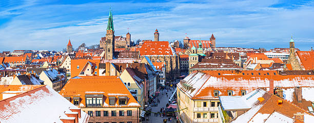 Aerial view over the old town of Nuremberg with the landmark St. Sebald´s church, Hauptmarkt (town square) with christmas market and stagecoach, the historic Chamber of Commerce, the town hall, the Church of our Lady and parts of the Kaiserburg castle in the distance on a beautiful cold winter day.