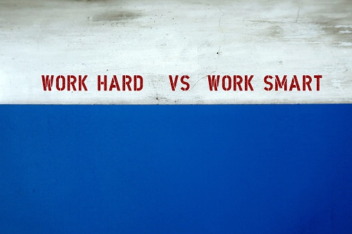 copy space blue and grey wall with text WORK HARD VS WORK SMART, means smart workers complete work within timelines using shortcut, proper planning or prior research instead of working long hours