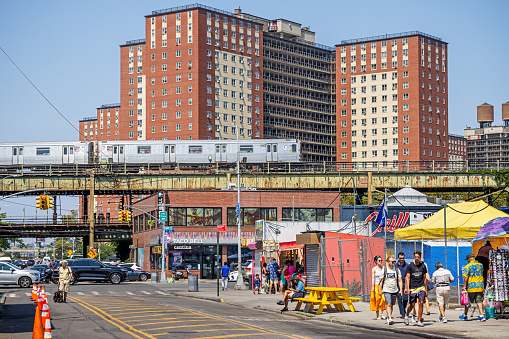 Coney Island, New York, USA - August 20th 2023:  Elevated subway train in front of residential building at a hot summers day