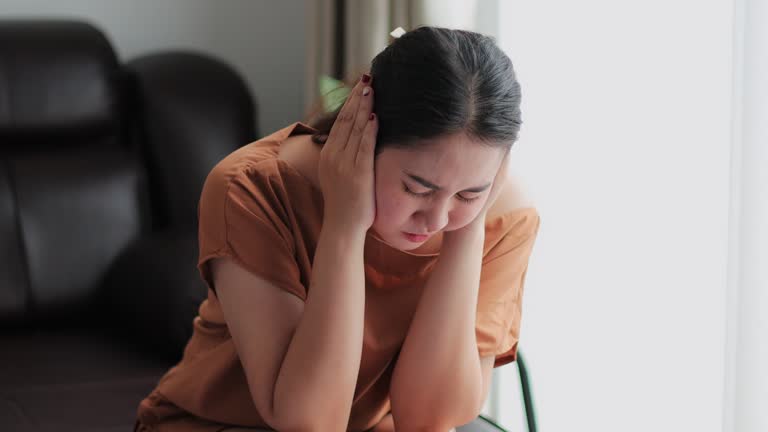 Tired stressed Asian young woman covering her ears with hands for stop listening to exhausted annoyed.