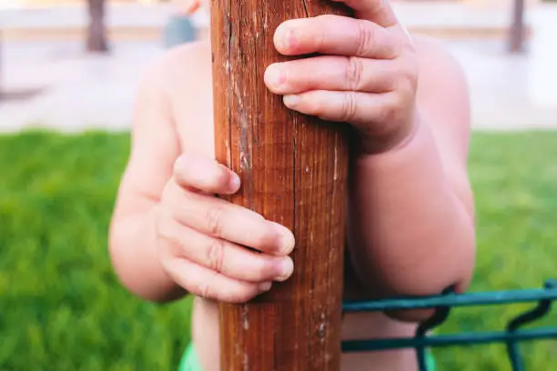Close-up of a baby's hand clutching a trunk to support his learning to walk.