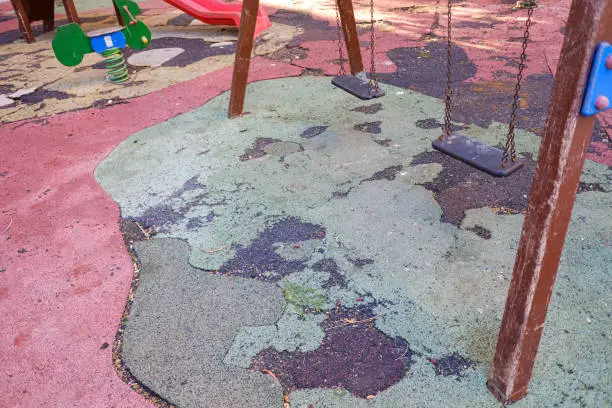 Neglected playground, with broken ground and in a dangerous state for children.