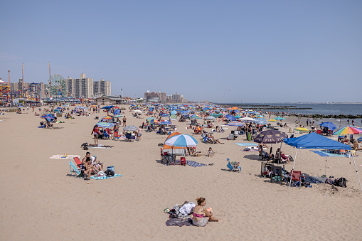 Coney Island, New York, USA - August 20th 2023:  People on the famous beach on a sunny day
