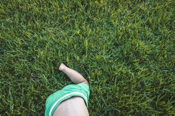 Baby crawling on the grass, with a green background with copy space.