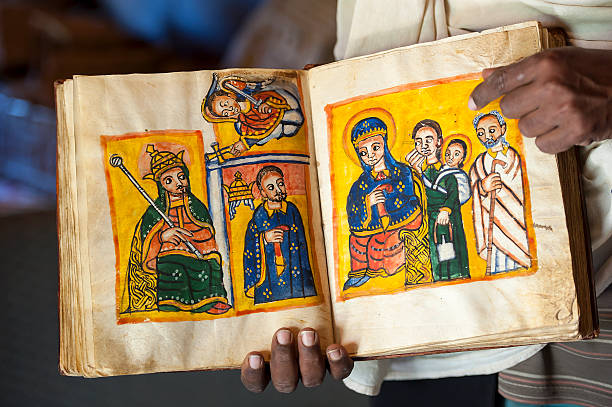 Priest is showing an ancient book in Ethiopia An old, handwritten and handpainted book (approx. 13th - 14th century). The book is written in the ancient language Geez, which is not used anymore except as liturgical language of the Ethiopian Orthodox Tewahedo Church.  circa 14th century stock pictures, royalty-free photos & images