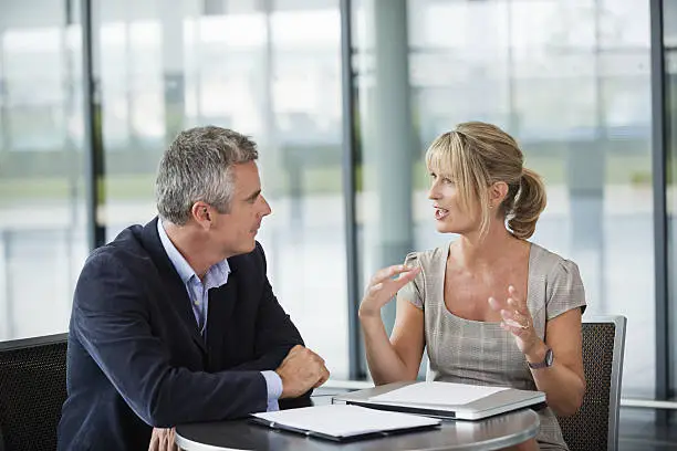 Businessman and woman having discussion at table in office.