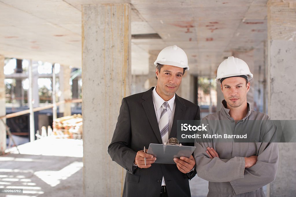 Operai edili in piedi insieme su luogo di costruzione - Foto stock royalty-free di 25-29 anni