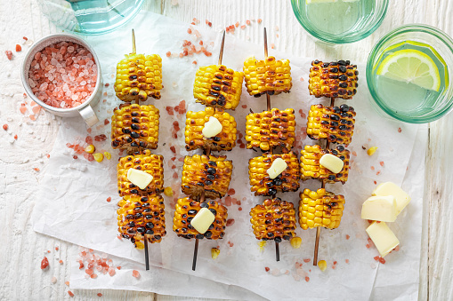 Hot grilled corn cob with salt, butter and herbs. Grilled cob served with butter and salt.