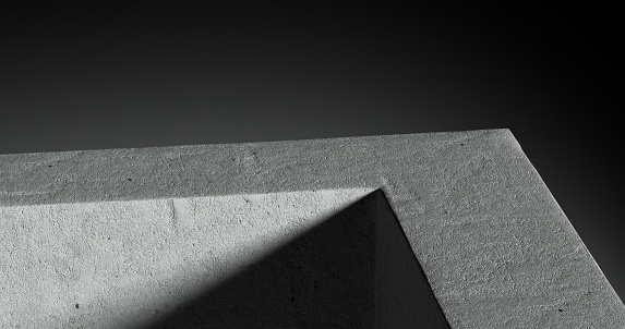 A close-up perspective of a concrete corner bathed in light, creating a striking contrast of varying shades from light to dark.