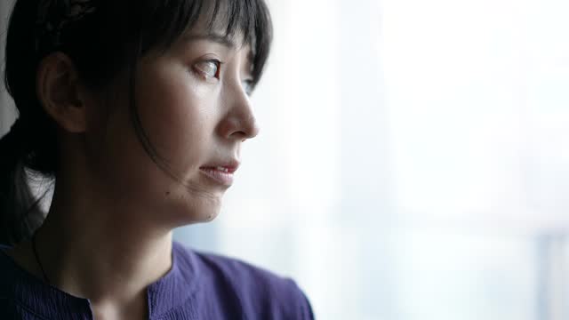 Close-up of a woman looking out the window with a sad expression