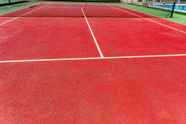 Background of a red cement tennis court in full sun in summer.