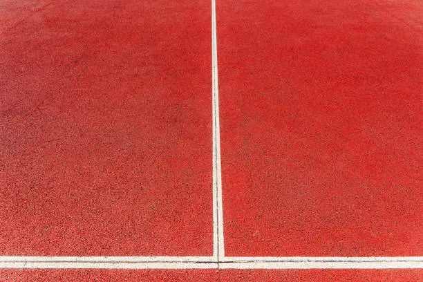 Background of a red cement tennis court in full sun in summer.