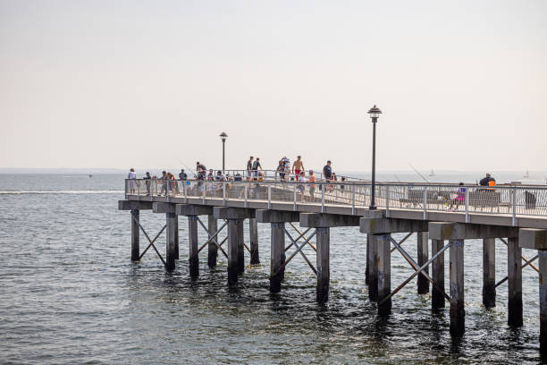 Coney Island, New York, USA - August 20th 2023:  Anglers on the wooden bridge at the Atlantic coast at the famous area
