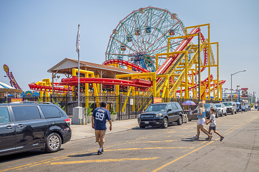 Coney Island, New York, USA - August 20th 2023:  Ferris wheel and colorful rollercoaster at the famous amusement district