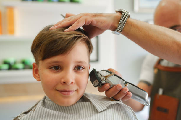 Little kid having a hair cut with hair clipper Part of a series of a boy having hair cut at the barber shop. teenager boy haircuts stock pictures, royalty-free photos & images