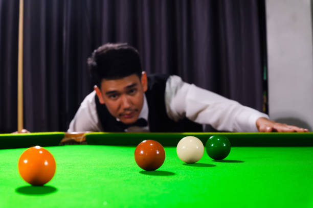 istock Snooker ball and snooker player with competitor blur while aiming black ball on snooker table in background. 1709813342