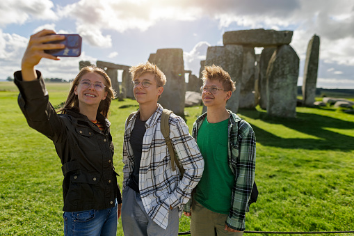 Teenage kids sightseeing Stonehenge, UK. Sunny summer day. Three teenagers are taking selfies.
Canon R5