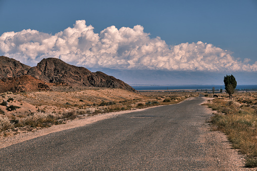 South bank of lake Issyk-Kul. Clouds above remote mountain ridge. Old road is under construction