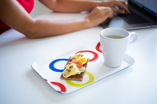 Young woman having breakfast while working on PC